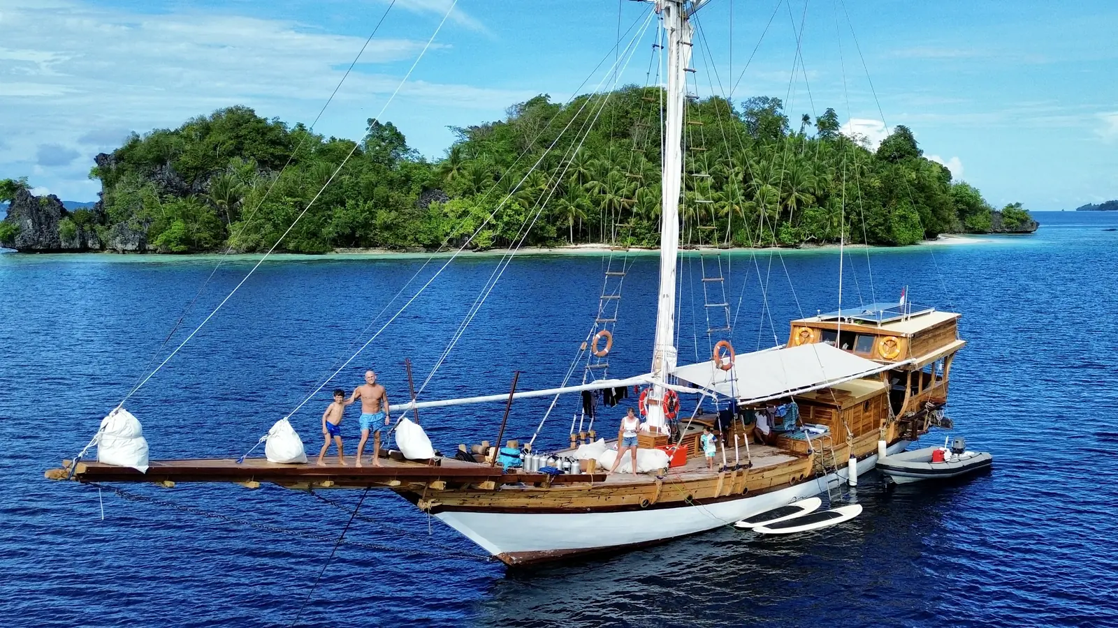 A family on the deck of a phinisi at anchor
