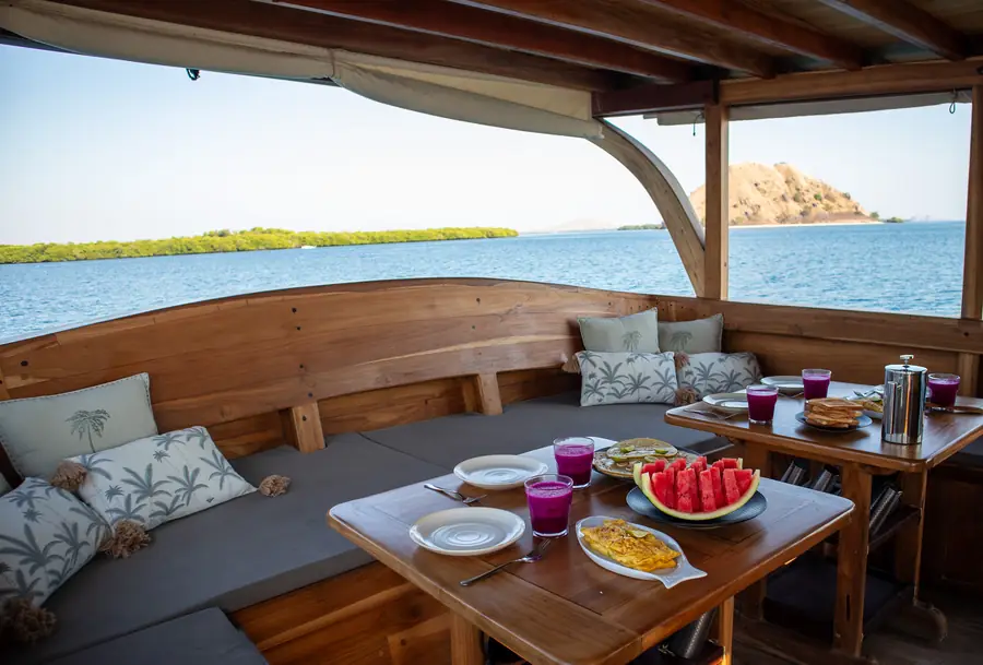 Breakfast laid out on the shaded deck of a small phinisi